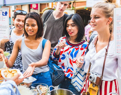 Tourists exploring Khao San Road, Bangkok, enjoying vibrant street food stalls.