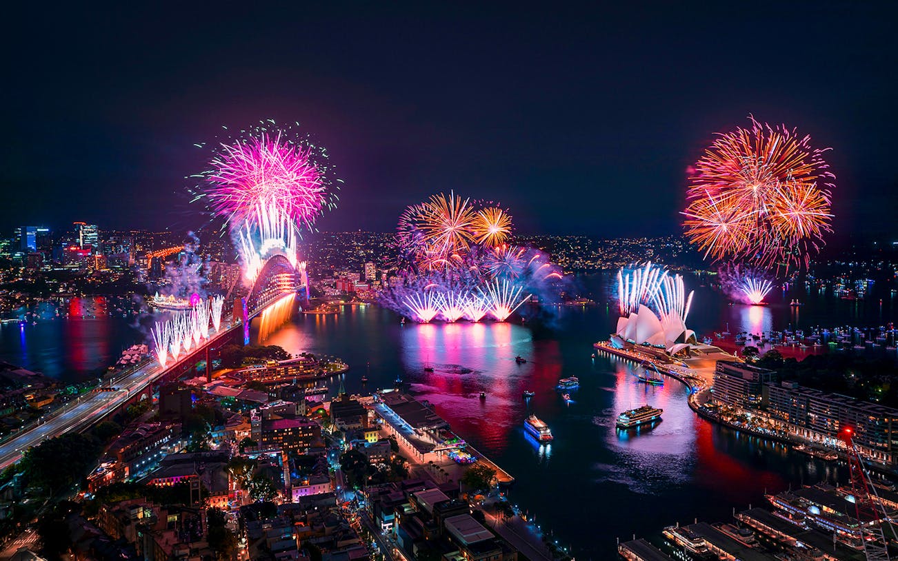 Sydney Harbour fireworks display with Opera House and bridge during New Year's Eve cruise.