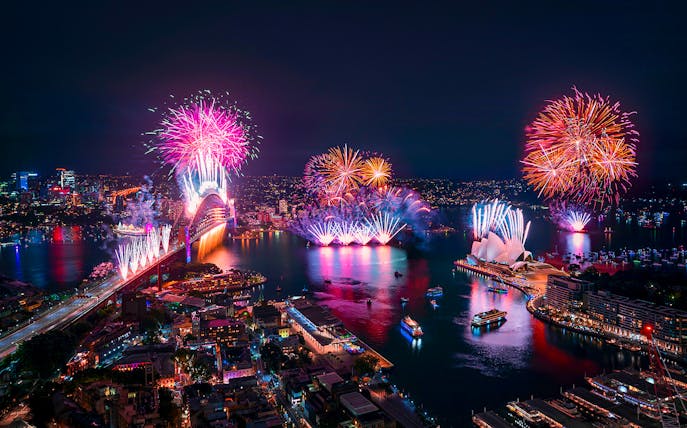 Sydney Harbour fireworks display with Opera House and bridge during New Year's Eve cruise.
