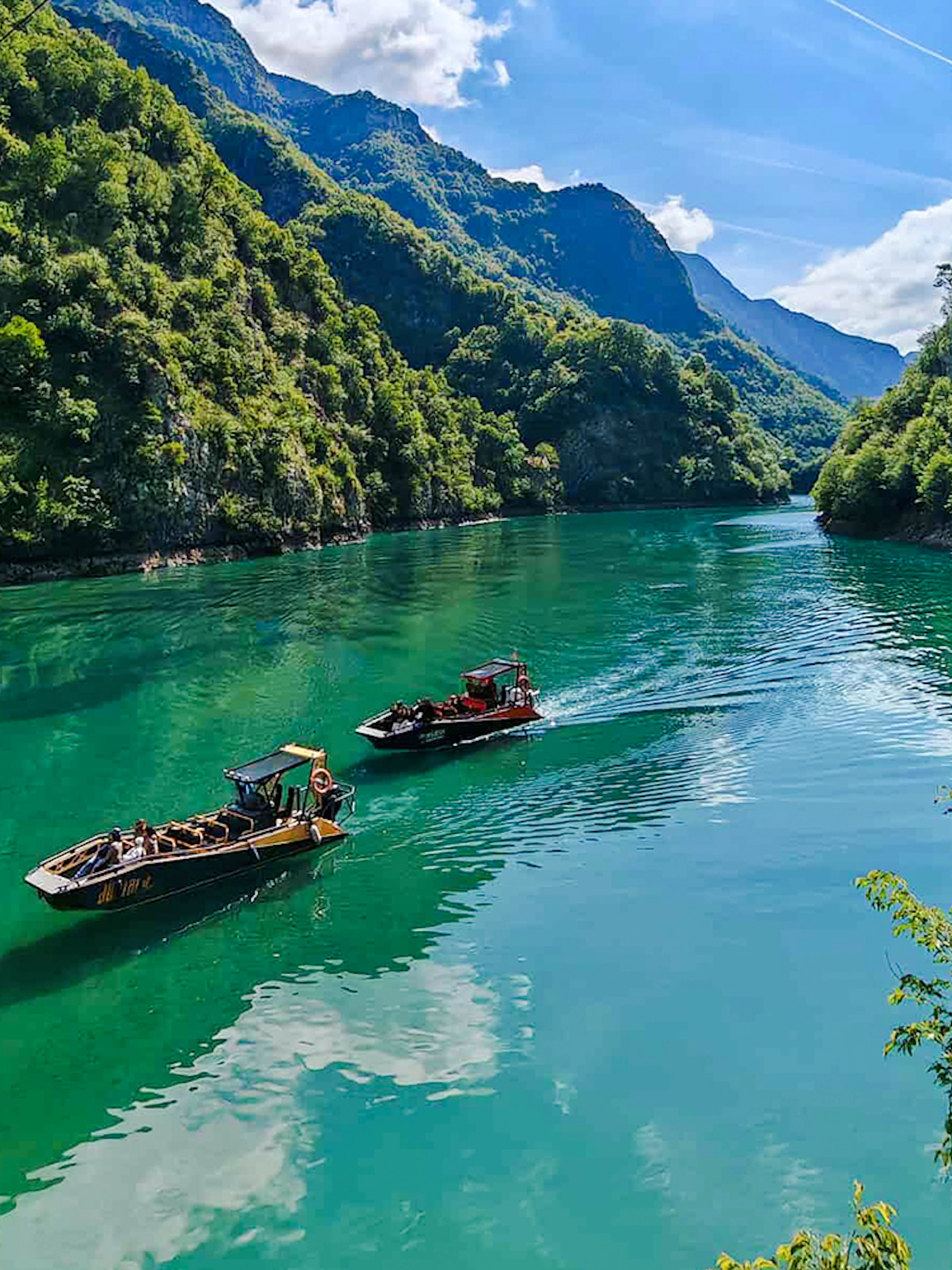 Guests on a boat tour in Komani Lake surrounded by lush green mountains.