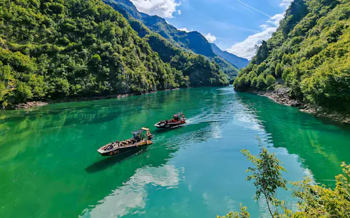 Guests on a boat tour in Komani Lake surrounded by lush green mountains.