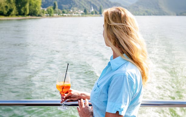 Woman enjoying a drink on a Koblenz sightseeing cruise.