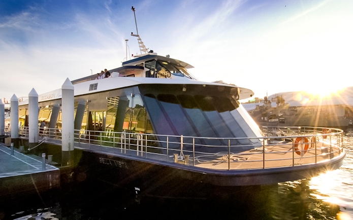 Glass boat docked in Sydney Harbor for Vivid Cruises at sunset.
