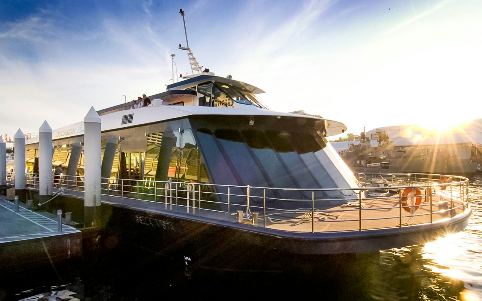 Glass boat docked in Sydney Harbor for Vivid Cruises at sunset.