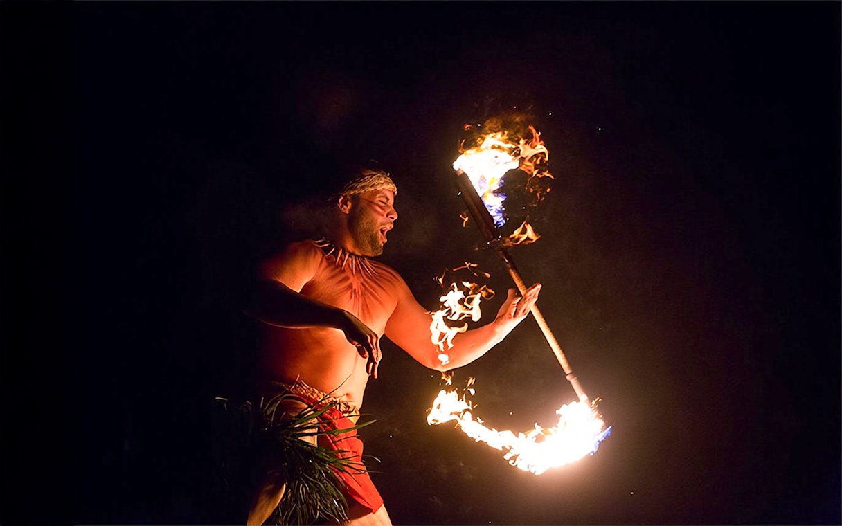 Fire dancer performing with flaming torch at Paradise Cove Luau, Hawaii.
