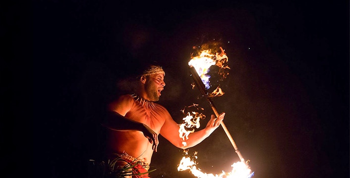 Fire dancer performing with flaming torch at Paradise Cove Luau, Hawaii.