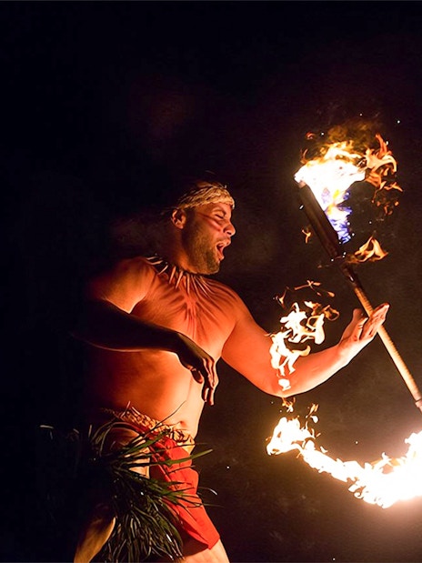 Fire dancer performing with flaming torch at Paradise Cove Luau, Hawaii.