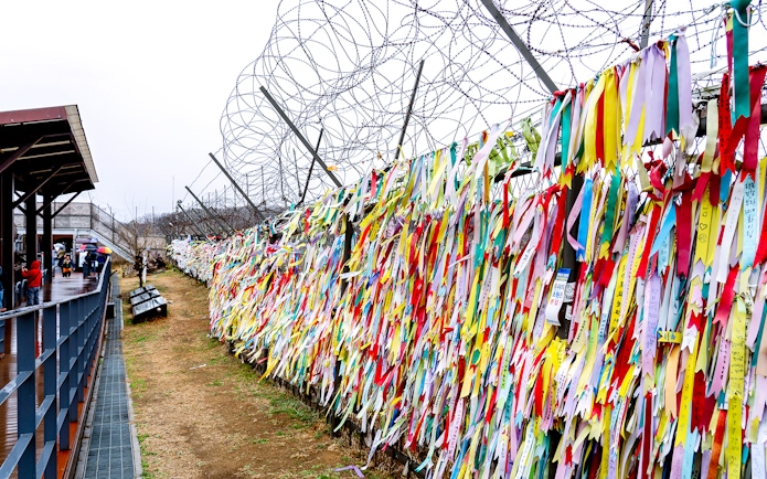 Colorful ribbons on barbed wire fence at Korean Demilitarized Zone during half-day tour.