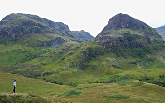 Person walking near the Three Sisters mountains in Glen Coe, Scotland.