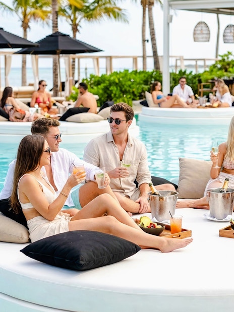 Group enjoying drinks on a floating island bed at FINNS Beach Party Lagoon Zone.