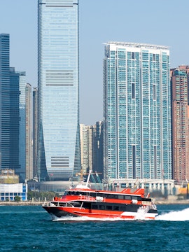 Ferry cruising in Victoria Harbour with Hong Kong skyline in the background.