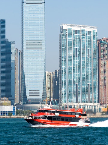Ferry cruising in Victoria Harbour with Hong Kong skyline in the background.