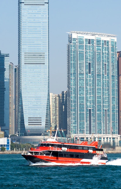 Ferry cruising in Victoria Harbour with Hong Kong skyline in the background.