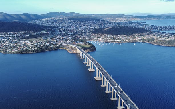 Aerial view of Tasman Bridge spanning the Derwent River in Hobart City, with surrounding suburbs.