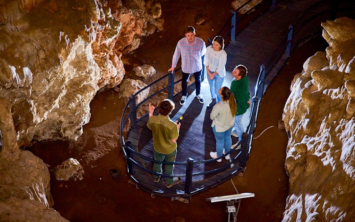 Group exploring Ngilgi Cave on a guided tour, standing on a walkway surrounded by rock formations.