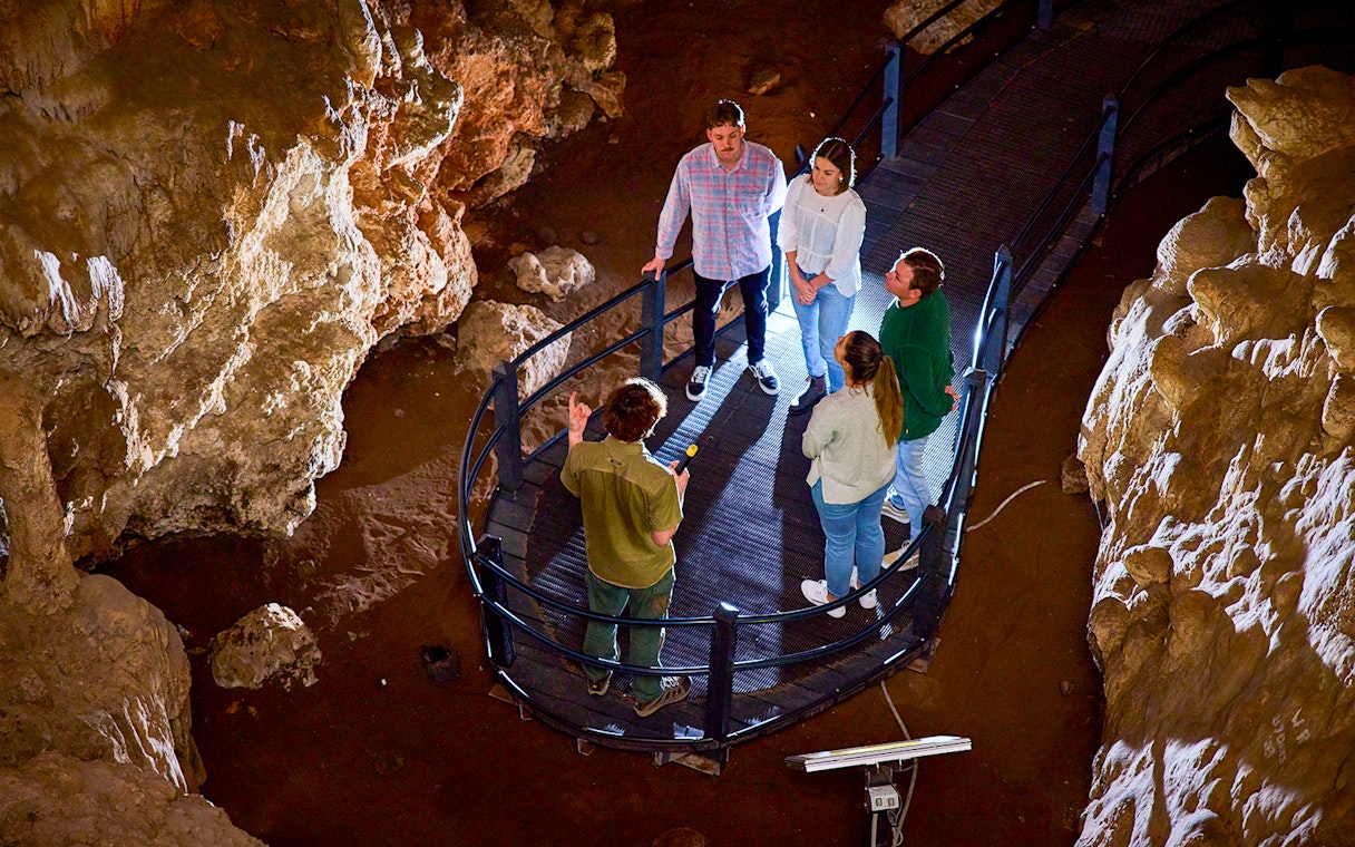 Group exploring Ngilgi Cave on a guided tour, standing on a walkway surrounded by rock formations.