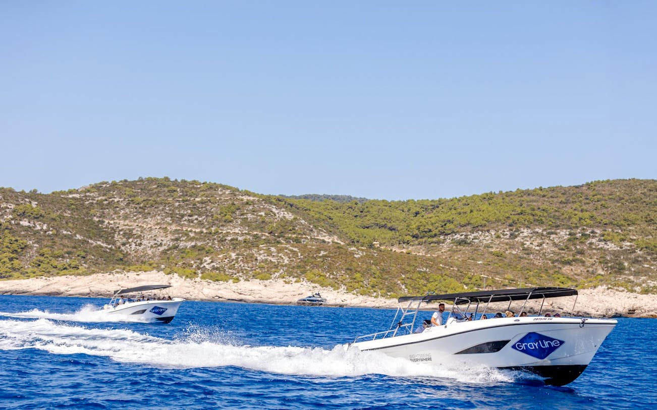 Speedboats cruising near rocky coastline during Blue Lagoon, Duga Bay, and Trogir Boat Tour.