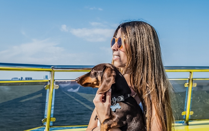 Tourist with her dog on a catamaran cruise, enjoying ocean views.