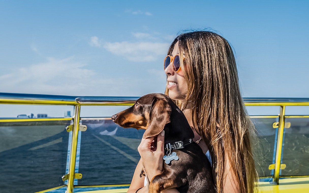 Tourist with her dog on a catamaran cruise, enjoying ocean views.