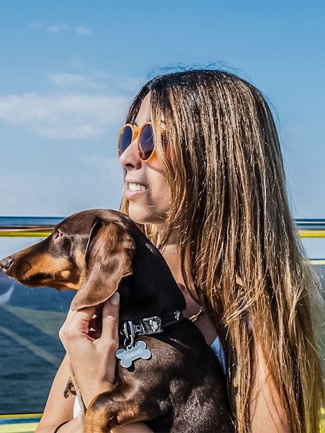 Tourist with her dog on a catamaran cruise, enjoying ocean views.