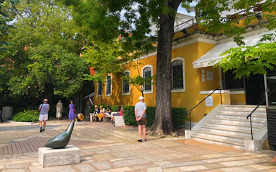Visitors outside the Peggy Guggenheim Collection in Venice, Italy, near a sculpture and yellow building.
