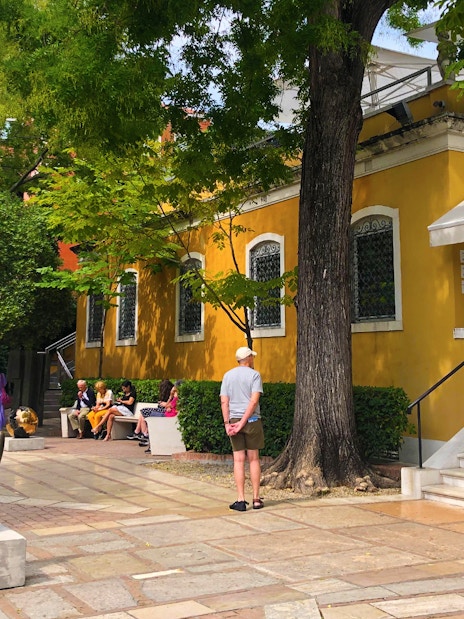 Visitors outside the Peggy Guggenheim Collection in Venice, Italy, near a sculpture and yellow building.