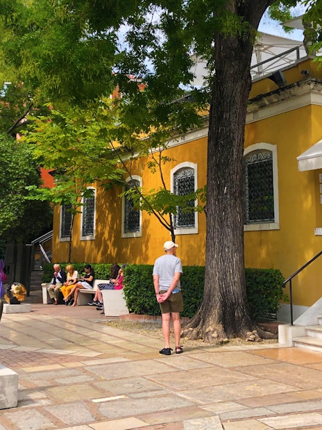 Visitors outside the Peggy Guggenheim Collection in Venice, Italy, near a sculpture and yellow building.