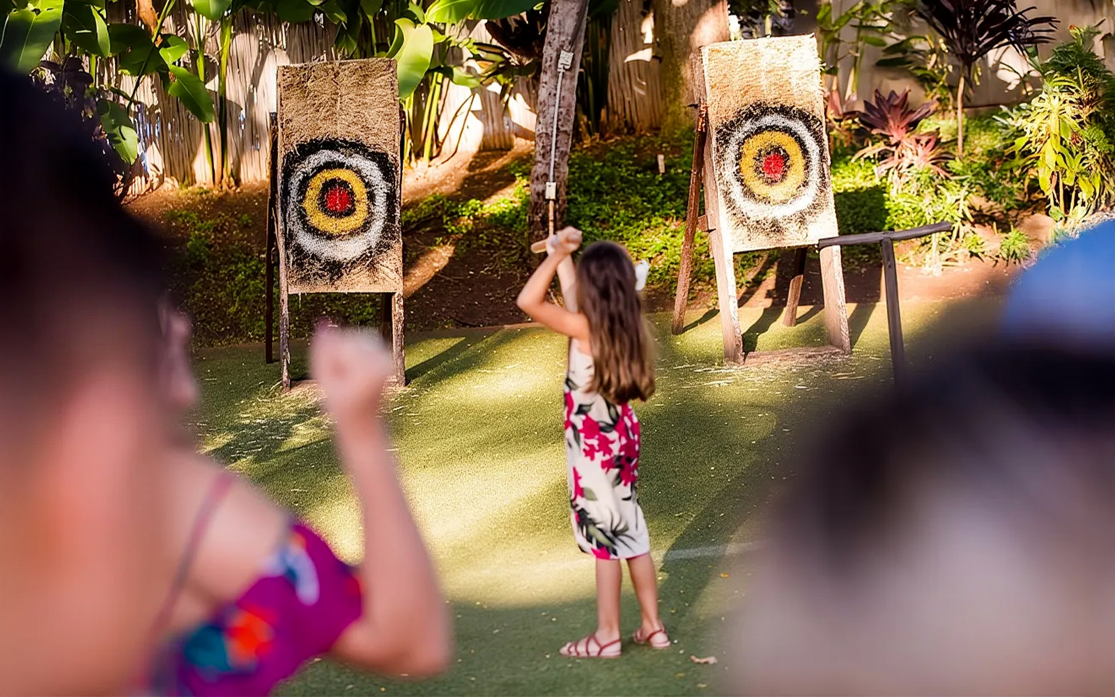 Guests engaging in spear throwing at Paradise Cove Luau, Hawaii.
