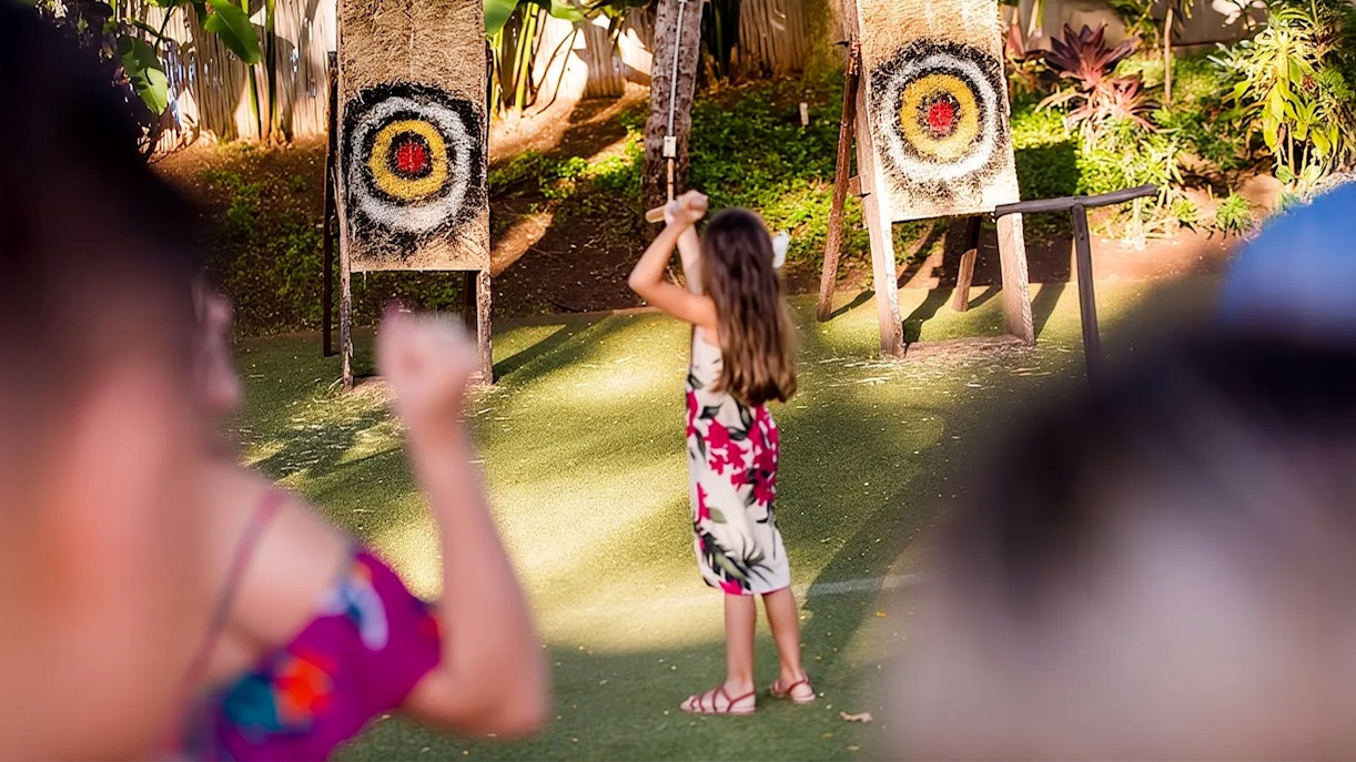 Guests engaging in spear throwing at Paradise Cove Luau, Hawaii.