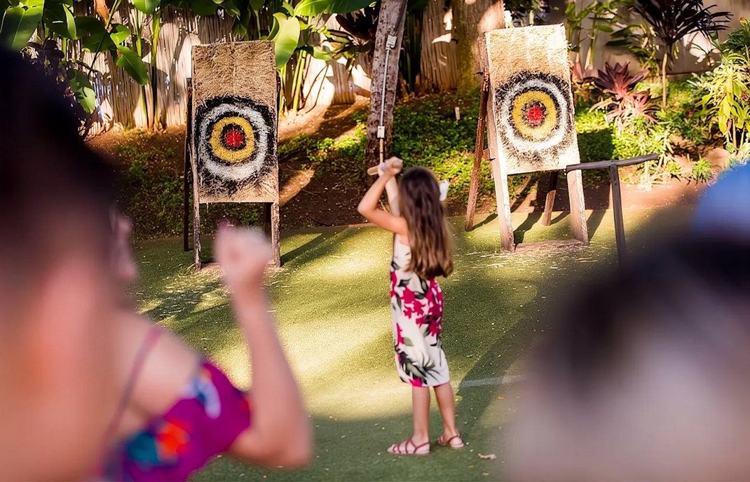 Guests engaging in spear throwing at Paradise Cove Luau, Hawaii.