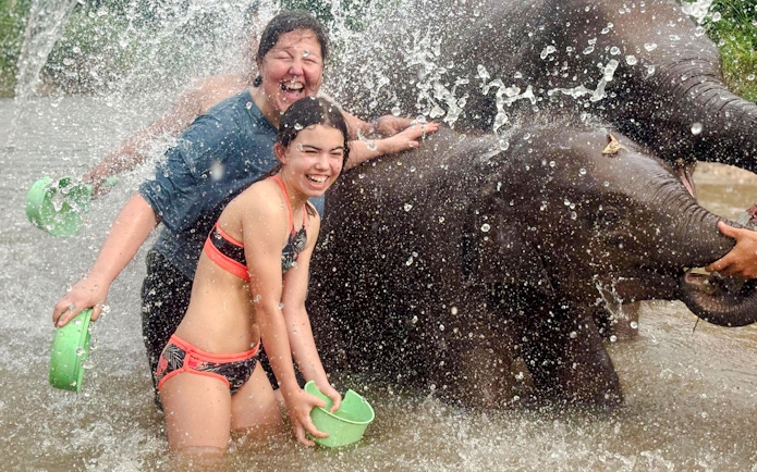 Visitors enjoying a water activity with elephants at Chiang Mai Elephant Sanctuary.