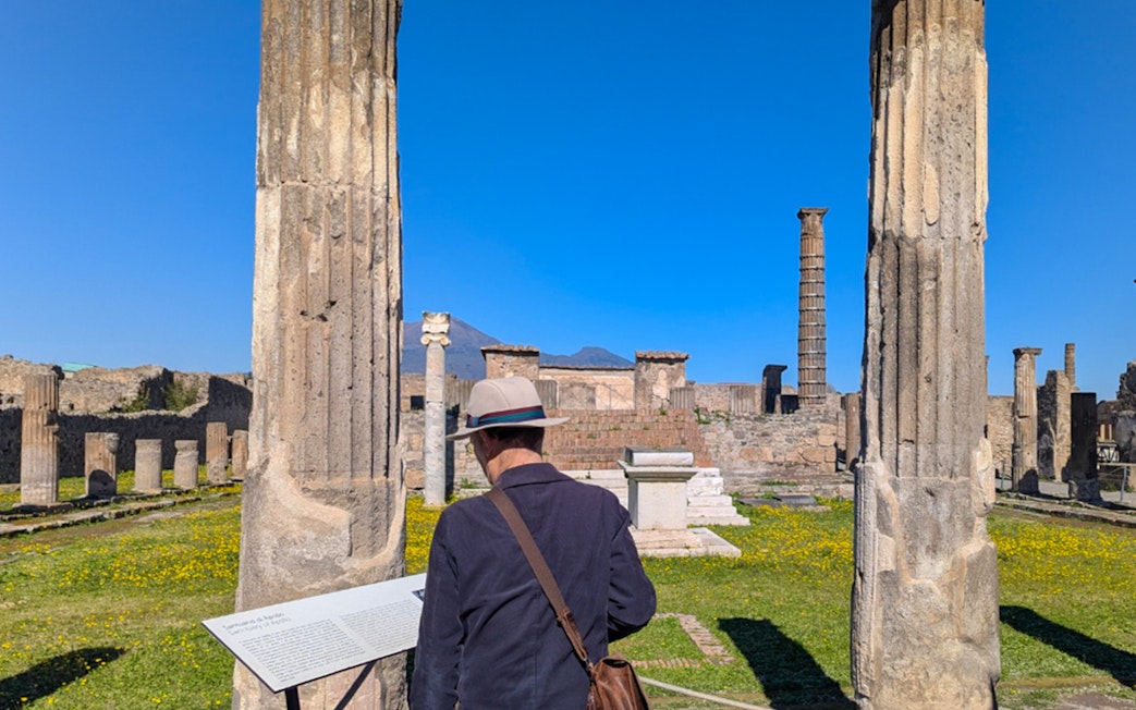 Man reading plaque at Temple of Apollo ruins in Pompeii, Italy.