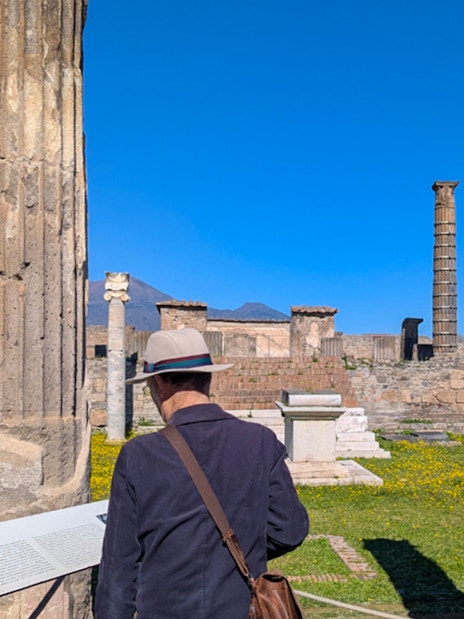 Man reading plaque at Temple of Apollo ruins in Pompeii, Italy.