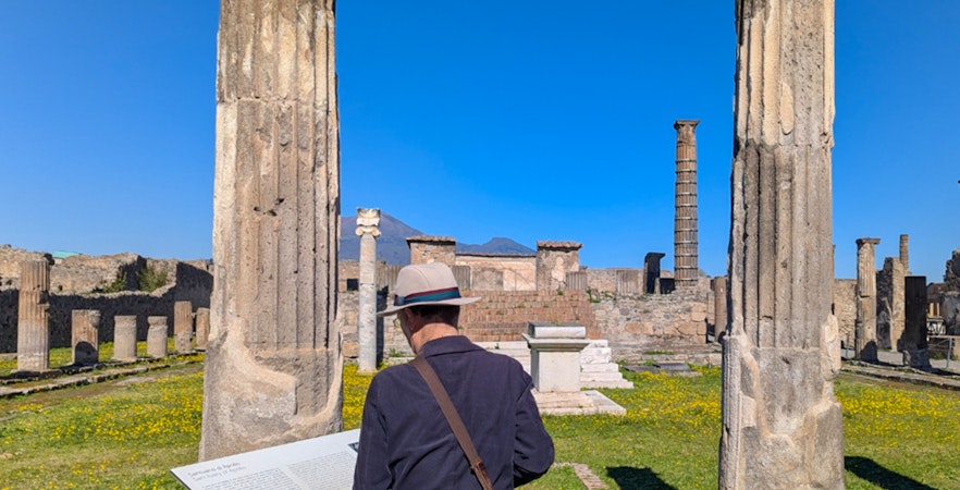 Man exploring ancient ruins at the Temple of Apollo in Pompeii, Italy.