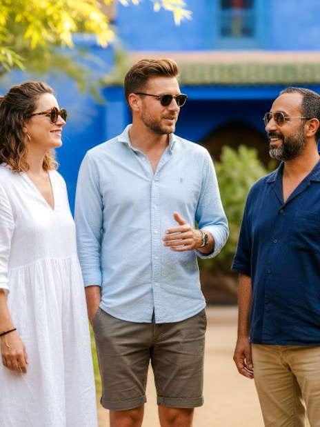 People with guide in Jardin Majorelle, Marrakech, surrounded by lush greenery and blue architecture.