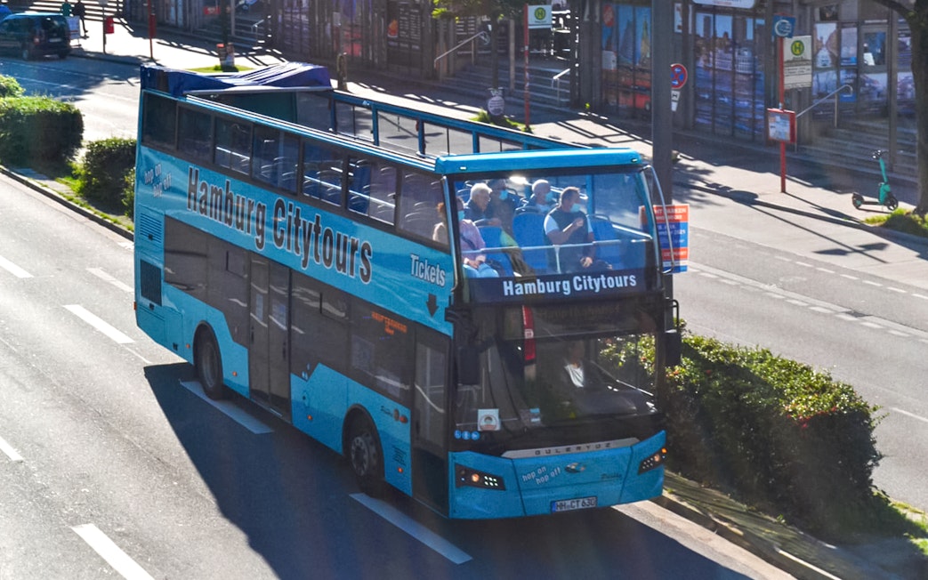 Hop-on hop-off bus touring Hamburg streets, offering city sightseeing.