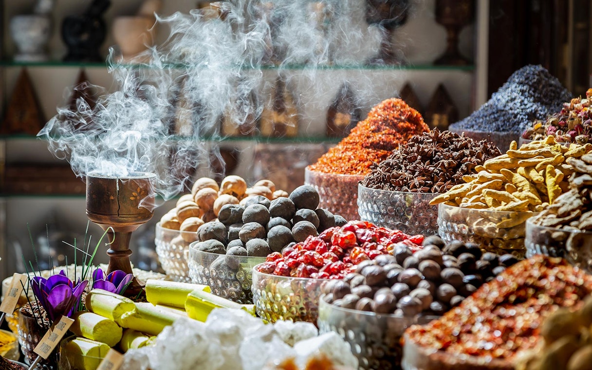 Spices and incense in Dubai souks, featuring colorful mounds and aromatic smoke.