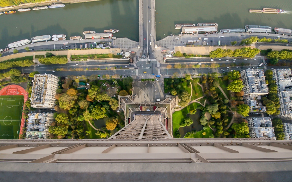 View from Eiffel Tower overlooking Paris street, river, and gardens.
