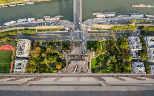View from Eiffel Tower overlooking Paris street, river, and gardens.