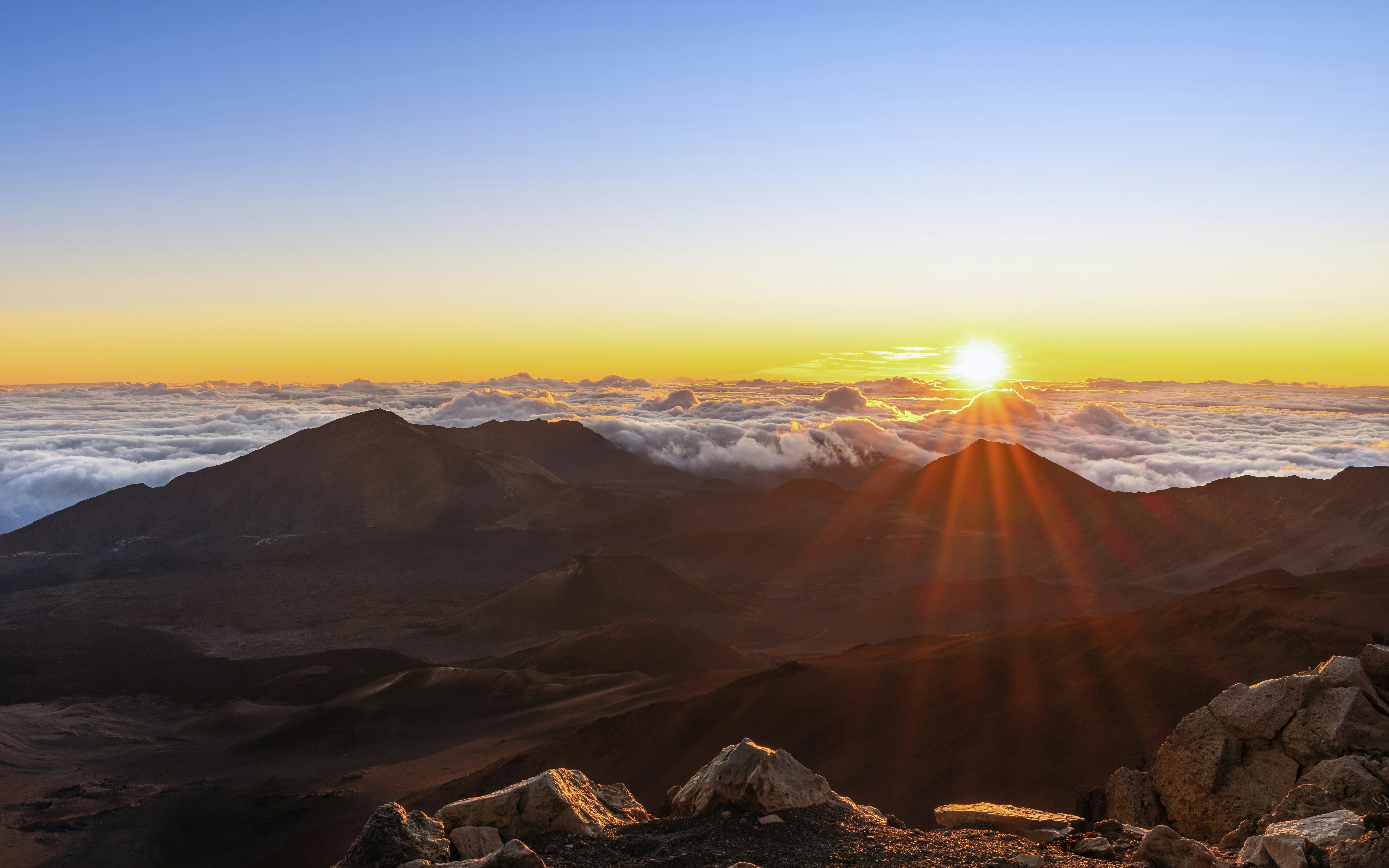 Sunrise over Haleakalā National Park with clouds and mountain peaks in Maui, Hawaii.
