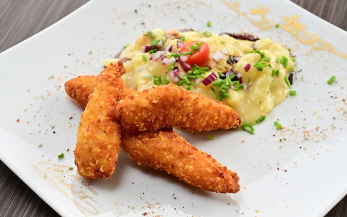 Crispy schnitzel with potato salad on a plate, served on a Vienna tour.