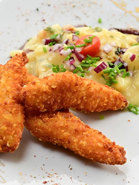 Crispy schnitzel with potato salad on a plate, served on a Vienna tour.
