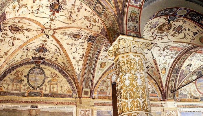 Palazzo Vecchio courtyard with intricate arches and frescoed ceilings in Florence, Italy.