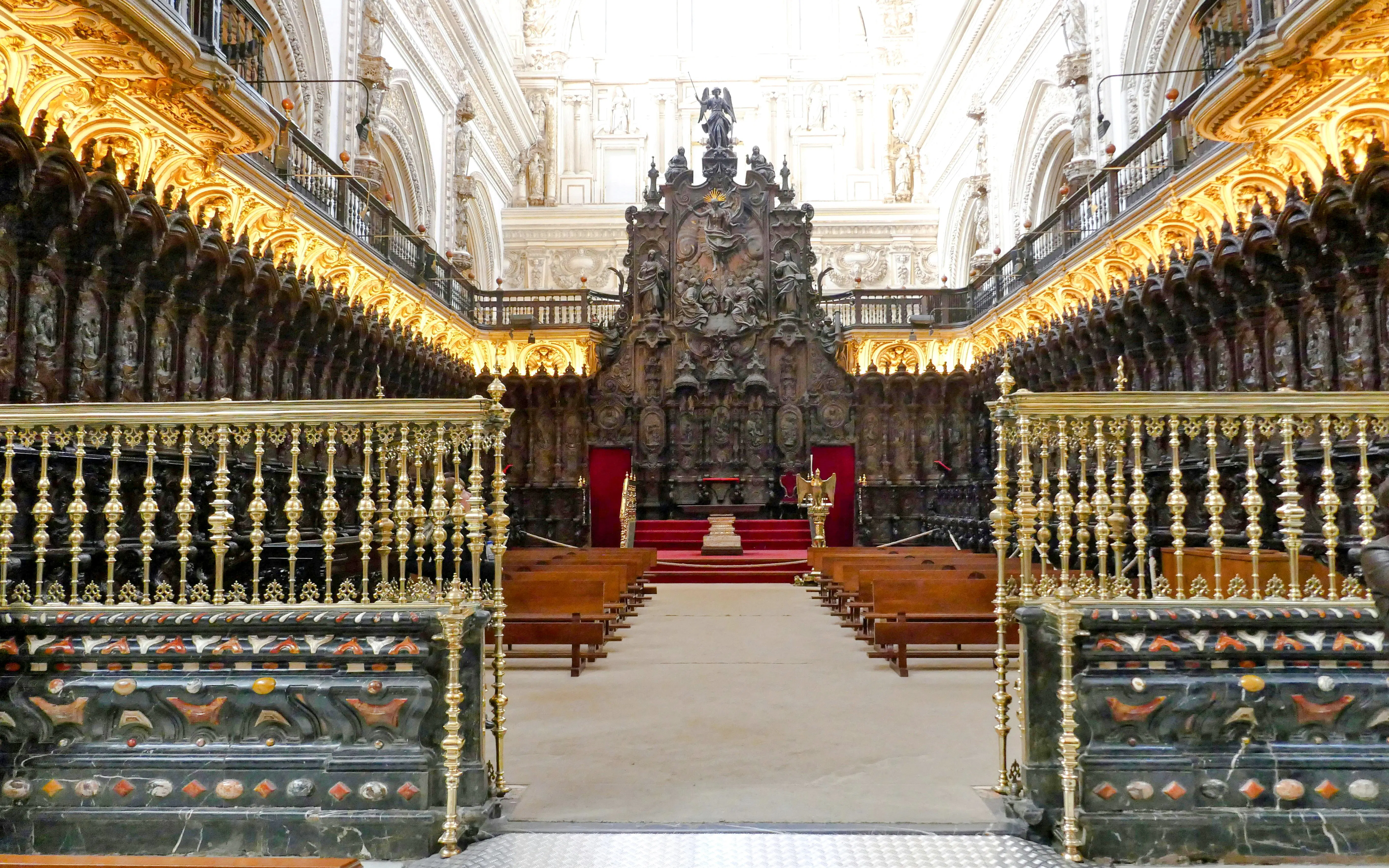 Choir stalls in the Cordoba Mosque with ornate carvings and golden railings.