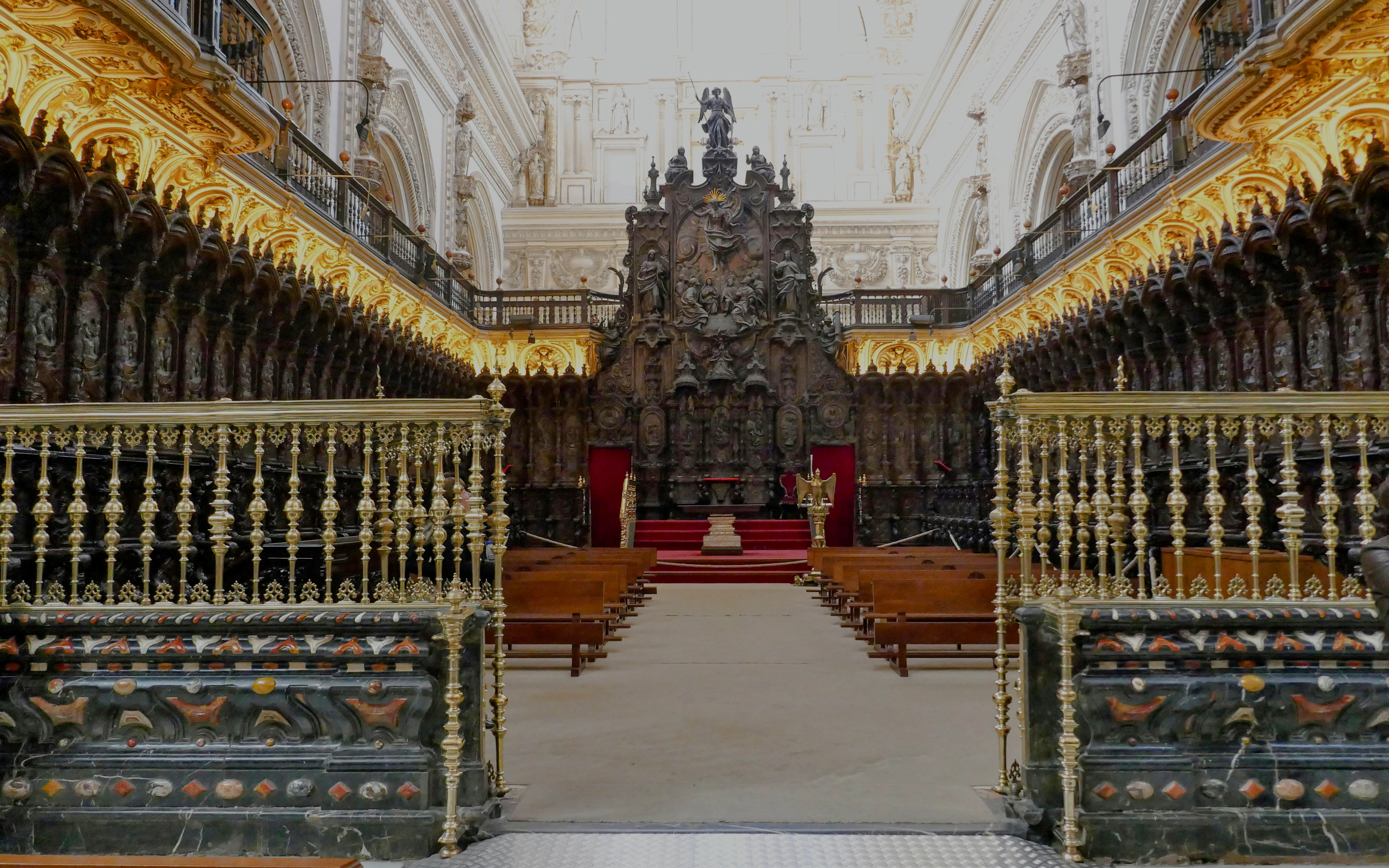 Choir stalls in the Cordoba Mosque with ornate carvings and golden railings.