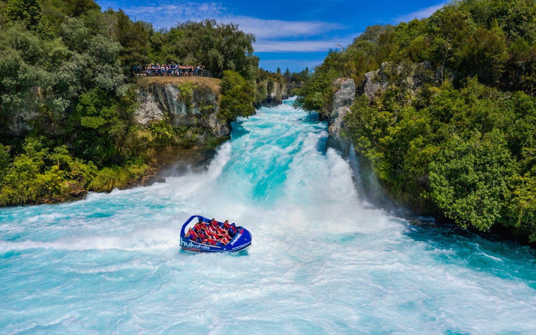 Tourists in a jet boat navigate rapids at Huka Falls, New Zealand.