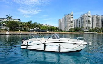 Speedboat "The Sun, Sea & Me" moored at Sentosa marina, Singapore, near waterfront apartments.