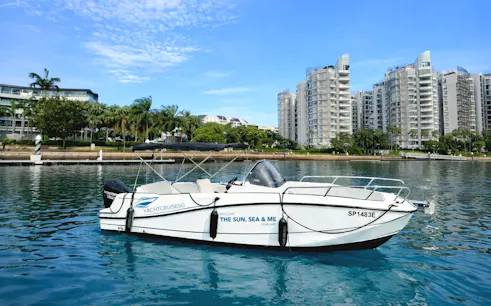 Speedboat "The Sun, Sea & Me" moored at Sentosa marina, Singapore, near waterfront apartments.