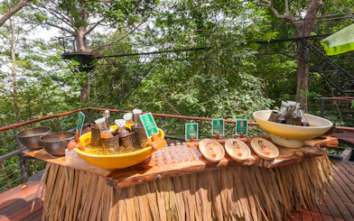 Juices and water on a wooden table at Hanuman World, surrounded by lush greenery.
