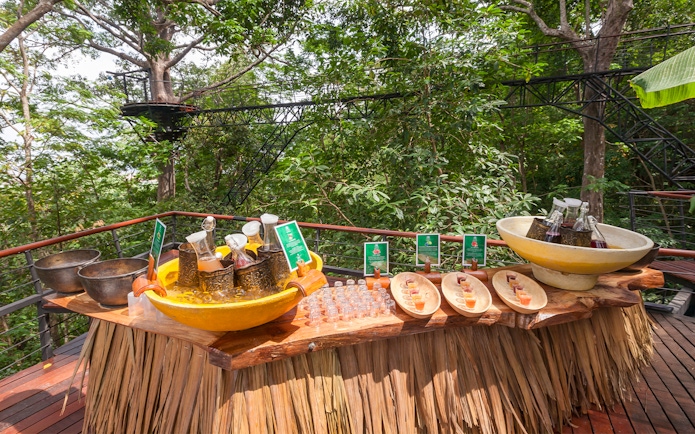 Juices and water on a wooden table at Hanuman World, surrounded by lush greenery.